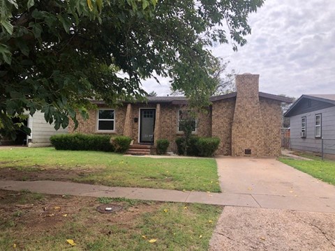 a brick house with a sidewalk in front of it