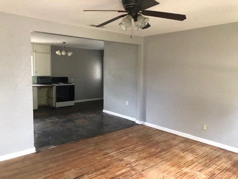 an empty living room with a ceiling fan