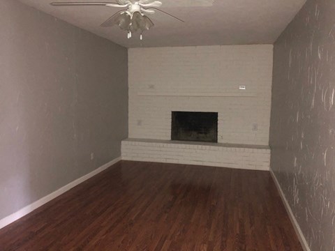 a living room with a white brick fireplace and wood floors