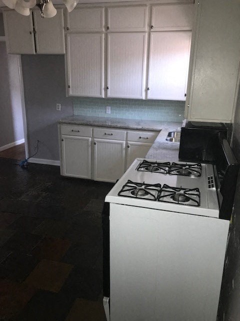 an empty kitchen with a stove and white cabinets
