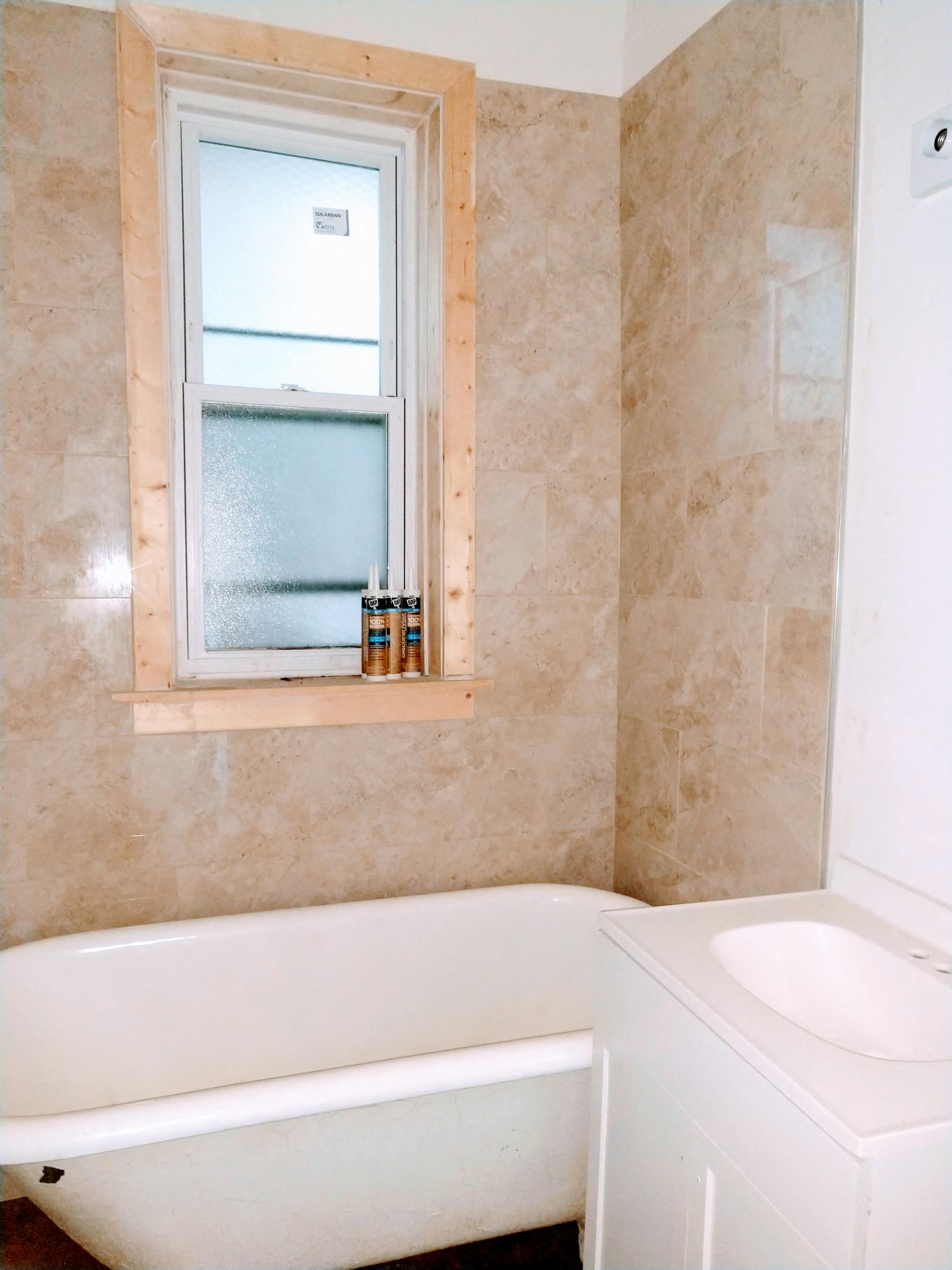 A bathroom with a tub, sink and window.