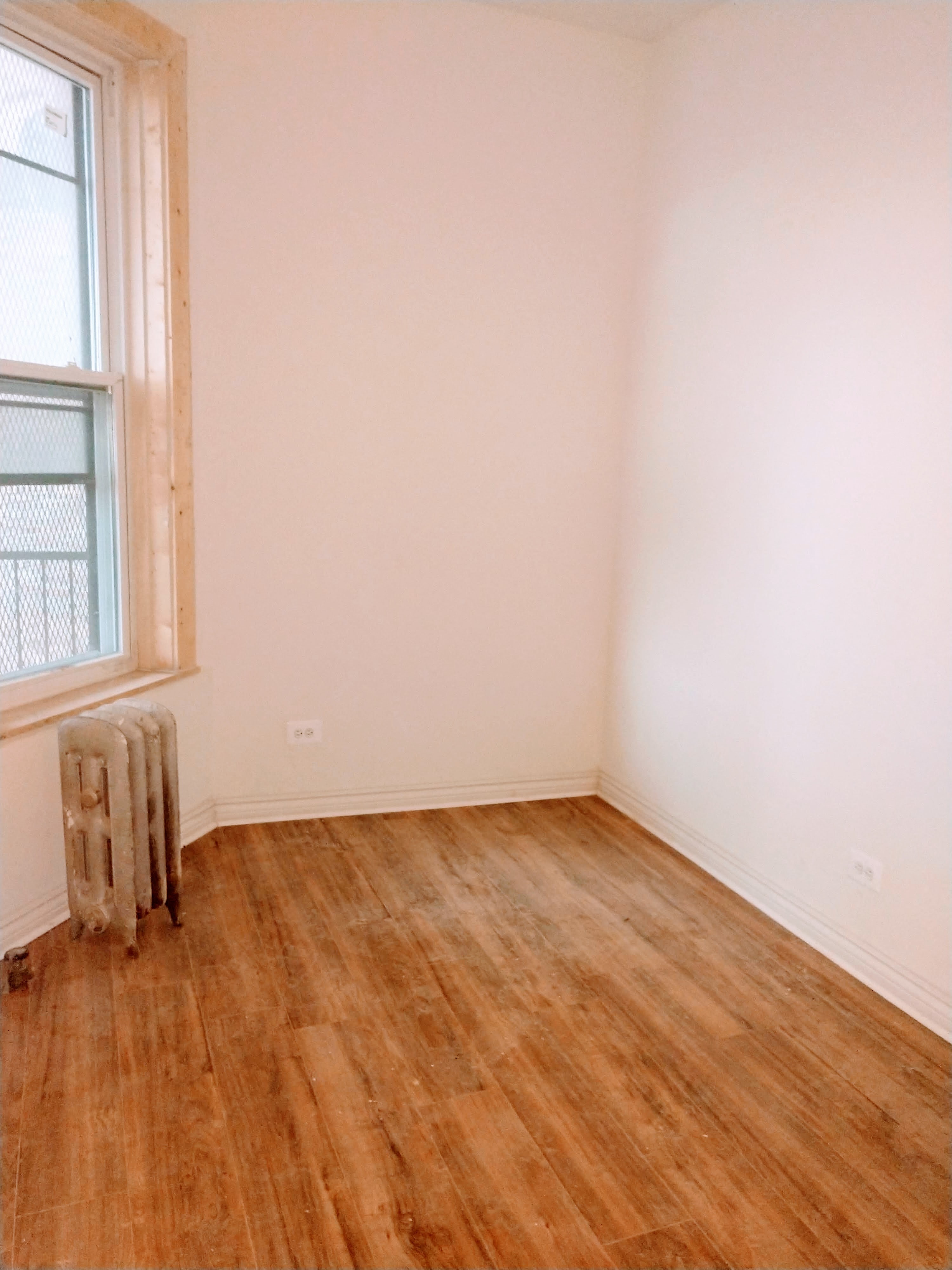 A room with a window and a radiator on the floor.