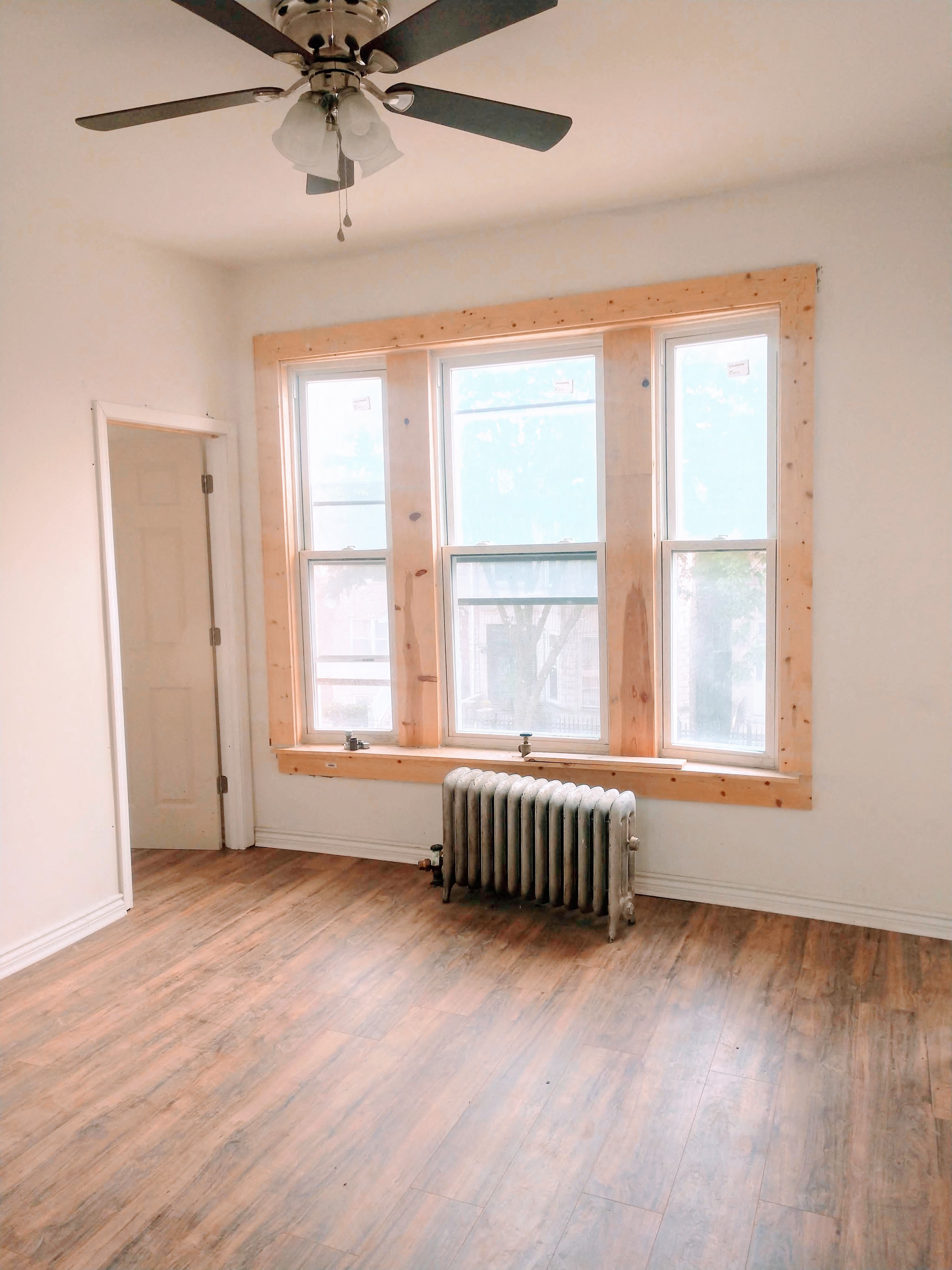 A room with a ceiling fan and a window with a radiator under it.
