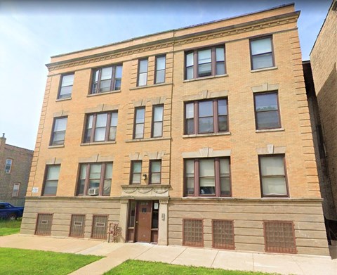A brown building with a green lawn in front.