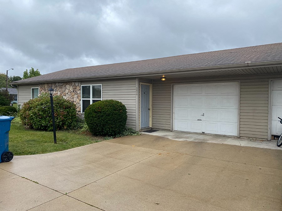 a small tan house with a white garage door