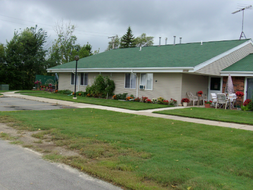 a house with a green roof on the side of a street