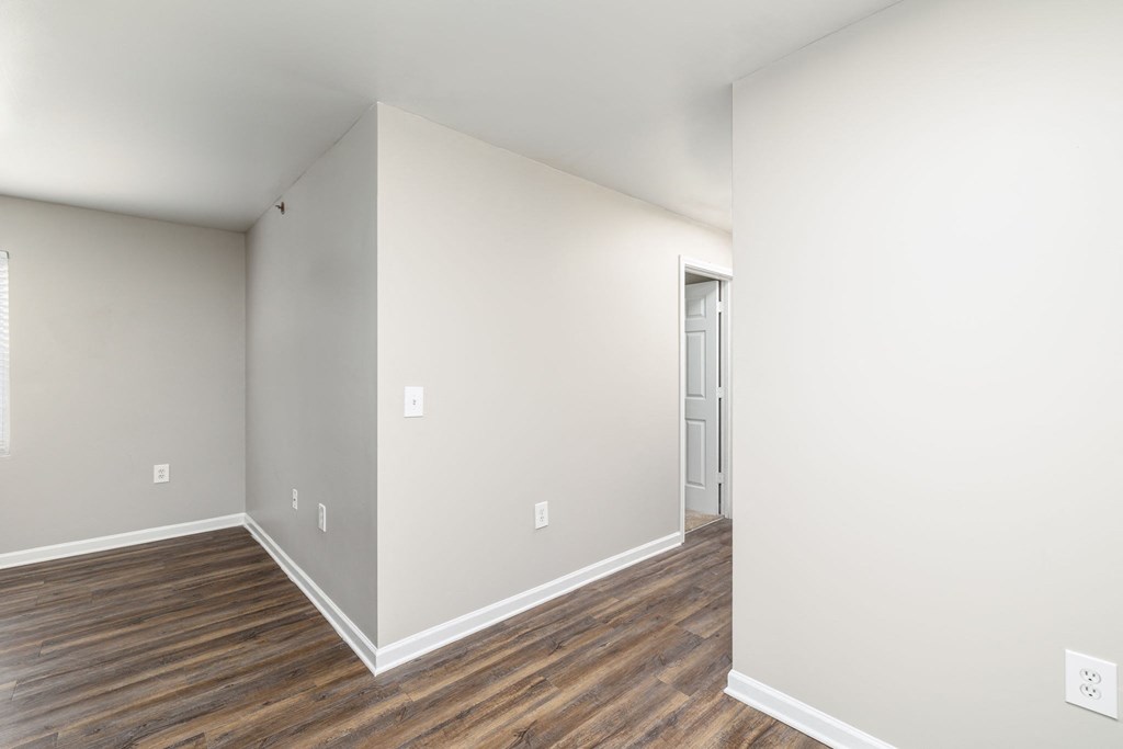 a bedroom with white walls and wood flooring and a closet