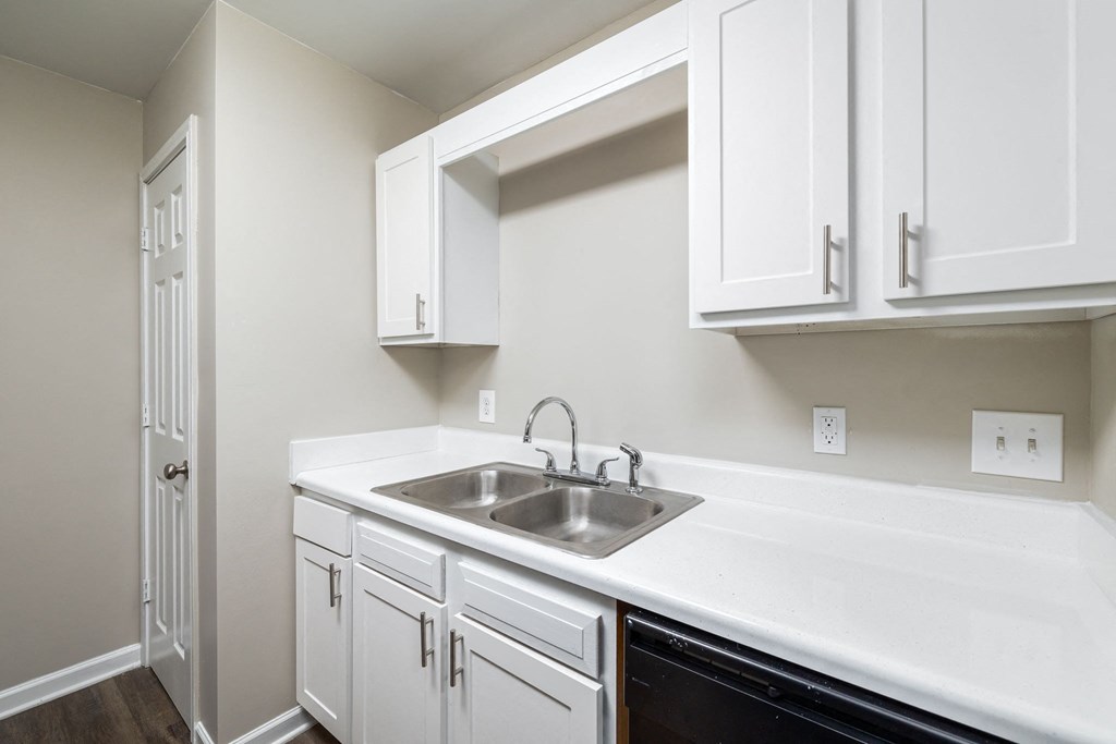 an empty kitchen with white cabinets and a sink