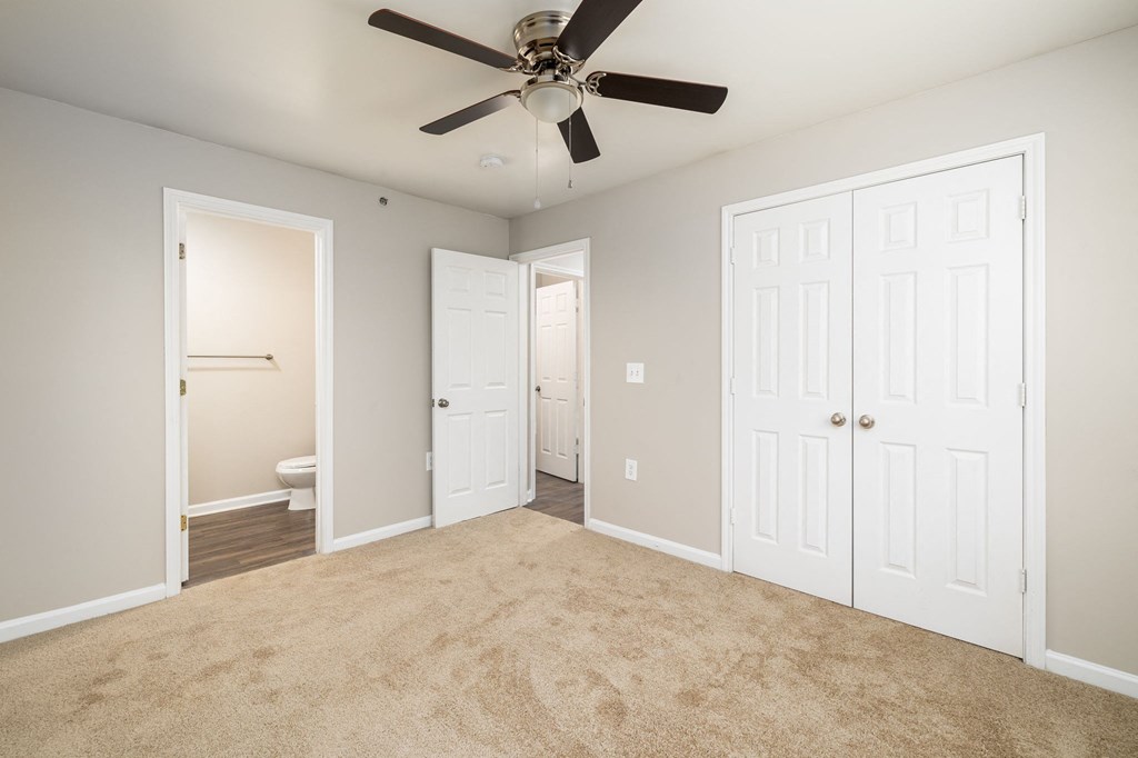 a bedroom with two closets and a ceiling fan