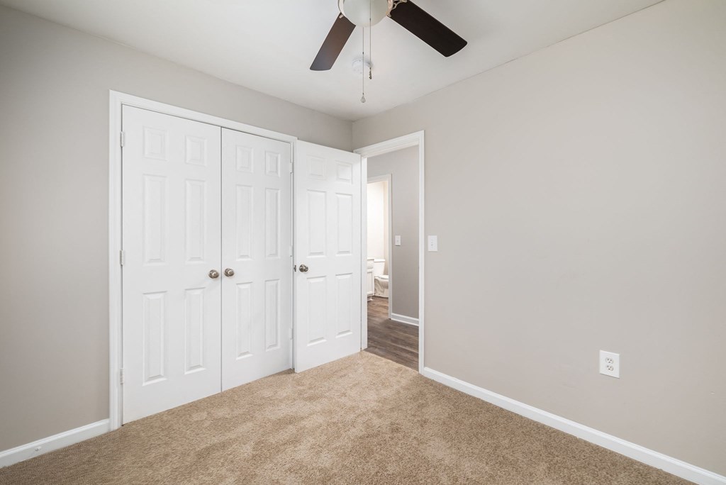 a bedroom with two closets and a ceiling fan