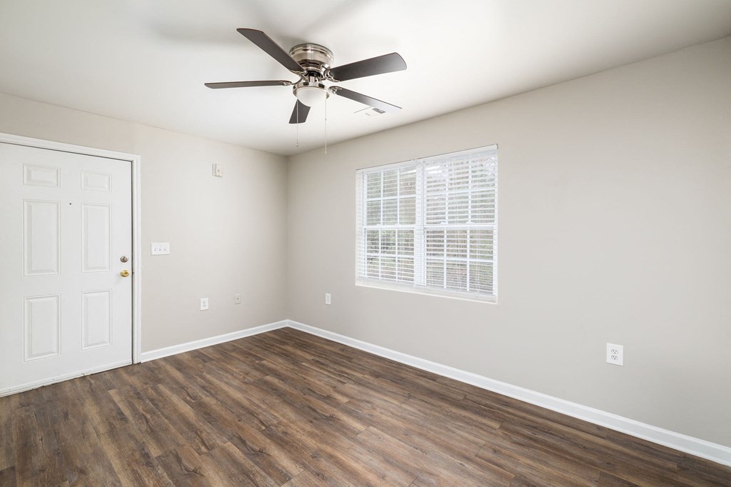 an empty living room with a ceiling fan and a window