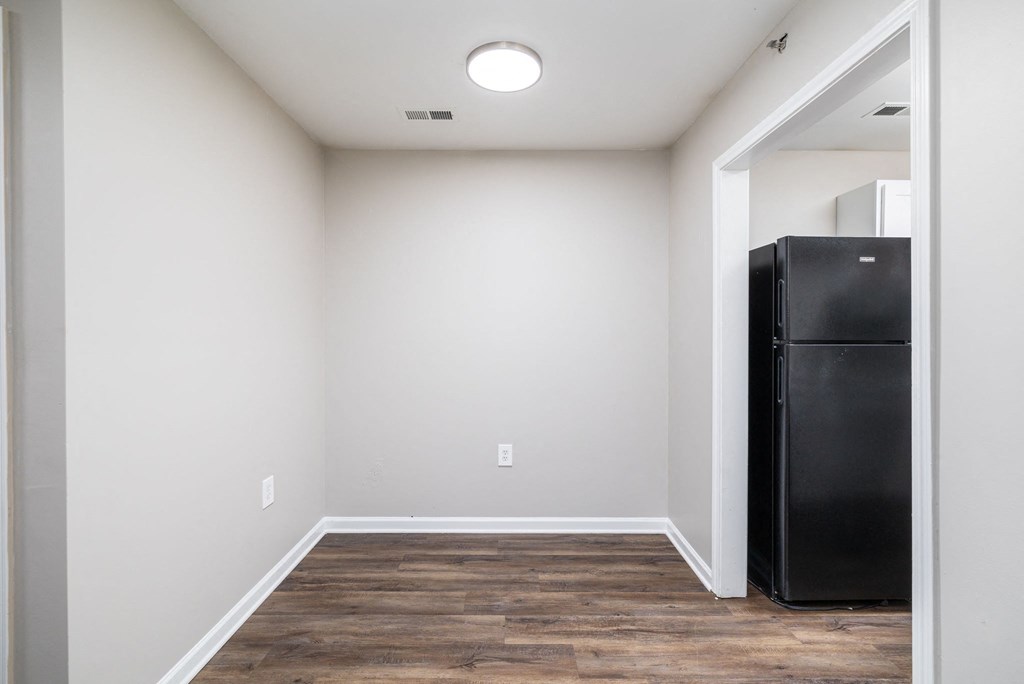 a room with white walls and a black refrigerator