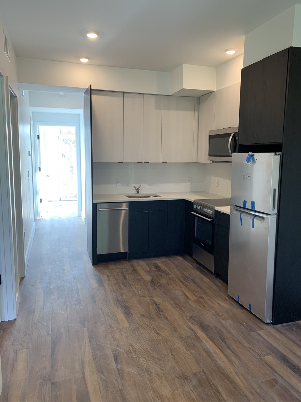 a renovated kitchen with black and white cabinets and stainless steel appliances