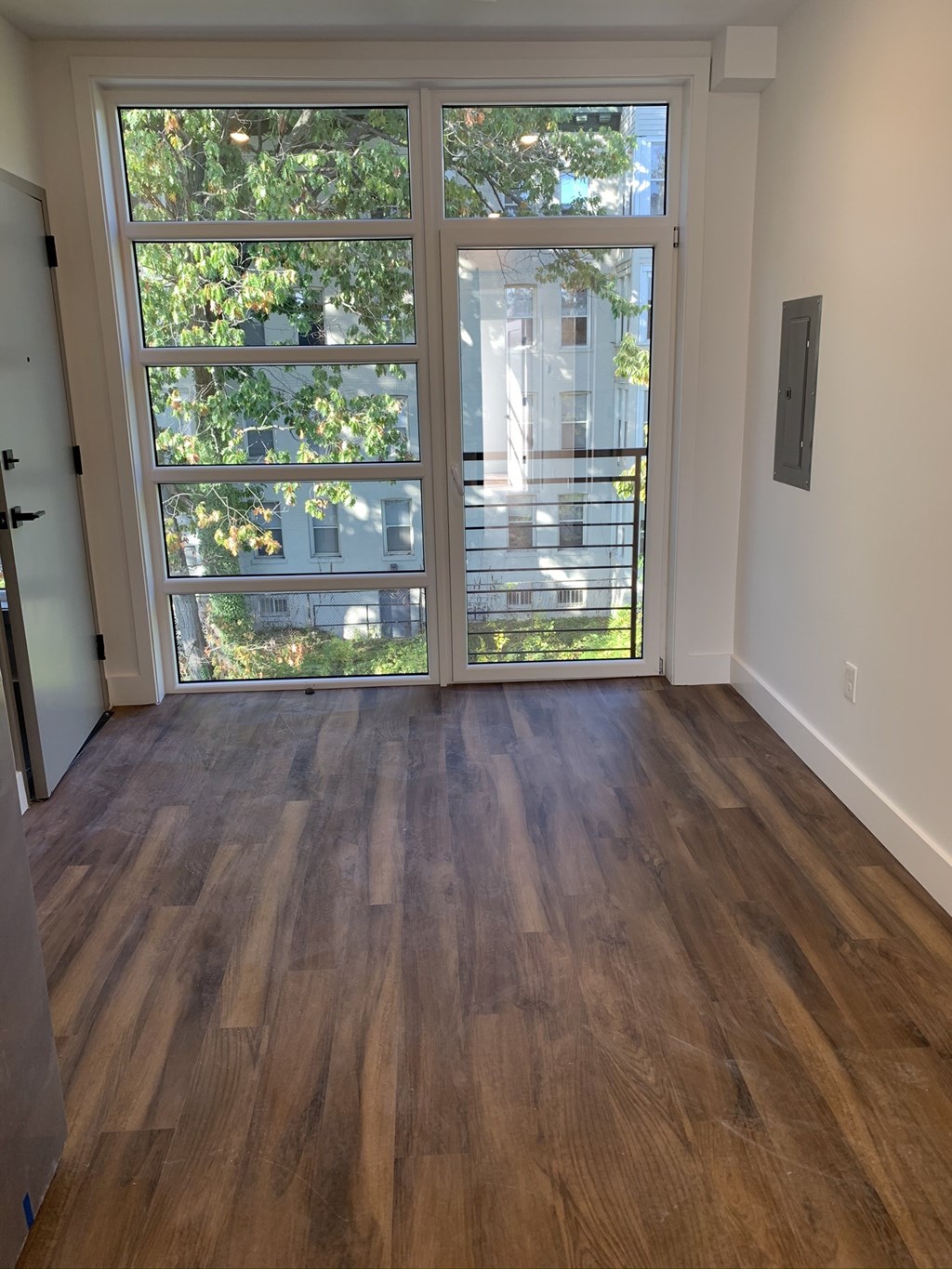 an empty living room with a large window and wooden floors