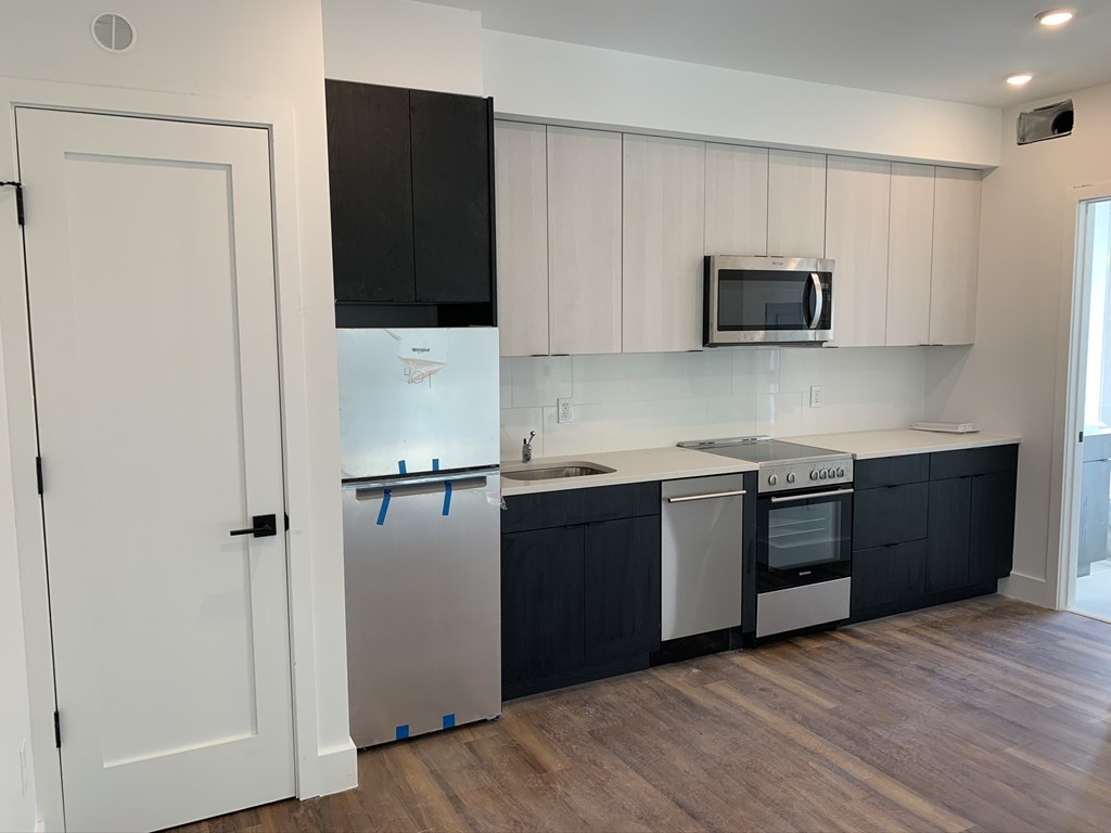 a renovated kitchen with white cabinets and black and white appliances