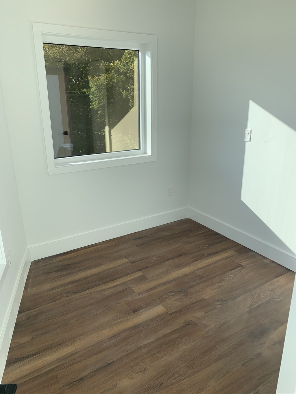 an empty room with wooden floors and a window