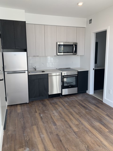 a kitchen with black and white cabinets and stainless steel appliances