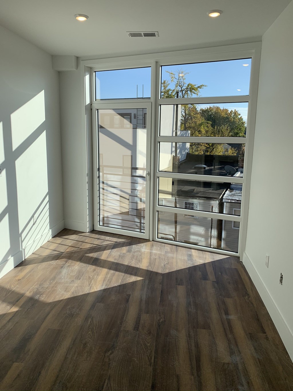 a living room with a hardwood floor and sliding glass doors
