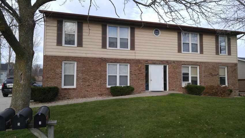 a brick house with a white door and a lawn
