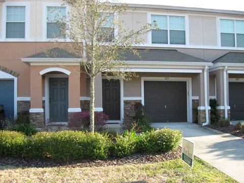 a house with black doors and a sidewalk in front of it