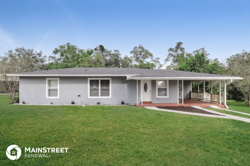 a small gray house with a lawn and a porch