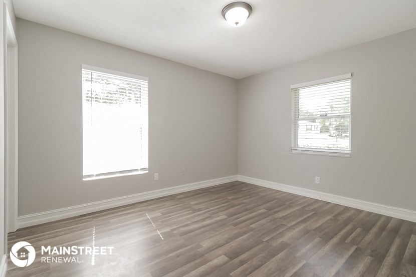 the spacious living room with wood flooring and two windows