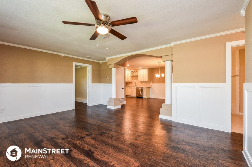 an empty living room with a ceiling fan