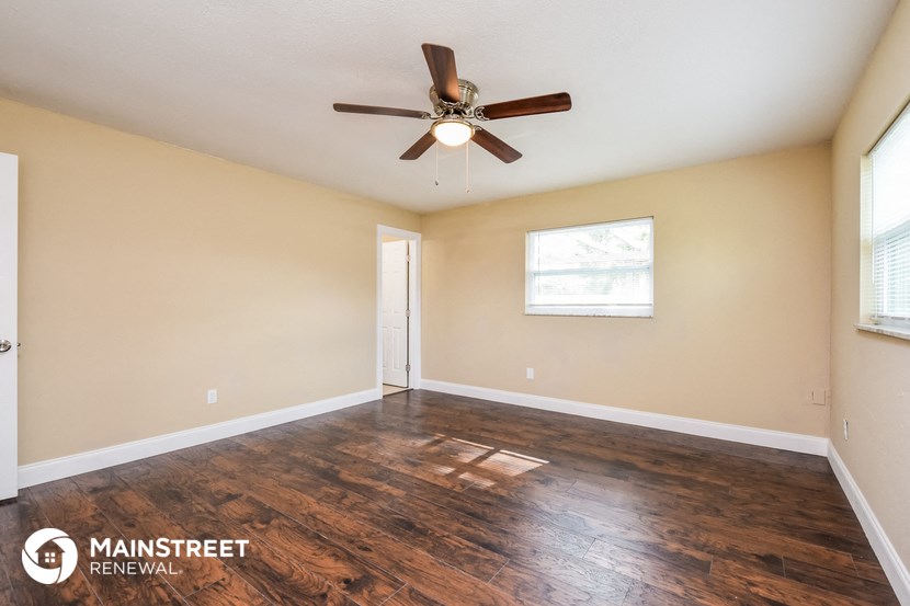the spacious living room with hardwood floors and a ceiling fan