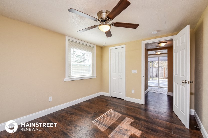 the living room is spacious and has a ceiling fan