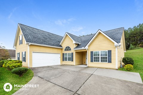 the front of a yellow house with a garage and a driveway