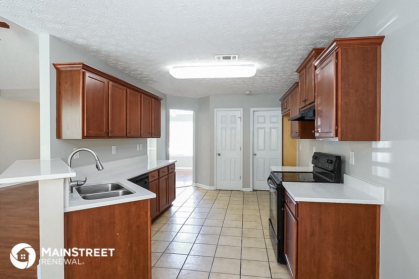 a kitchen with wooden cabinets and white counter tops and a sink