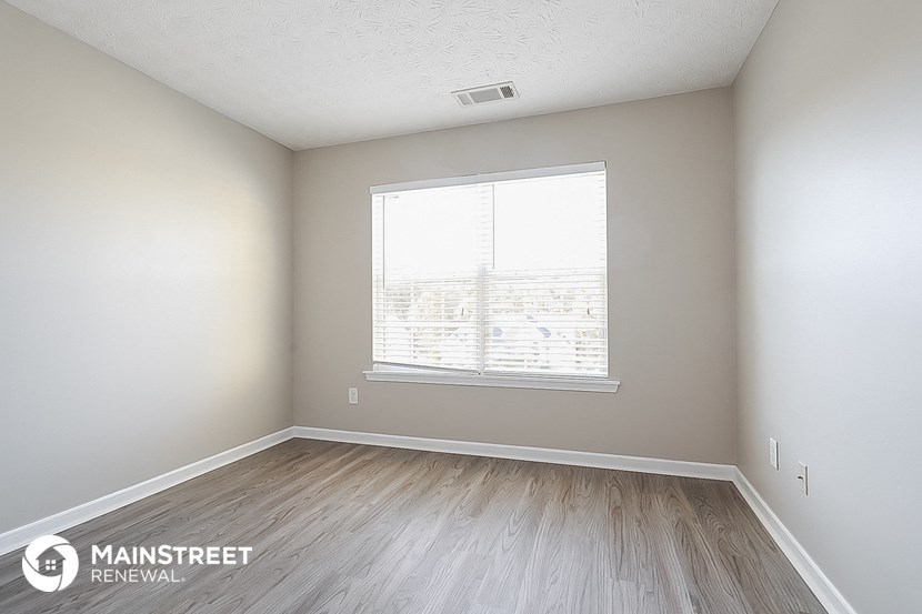 the spacious living room with wood floors and a large window