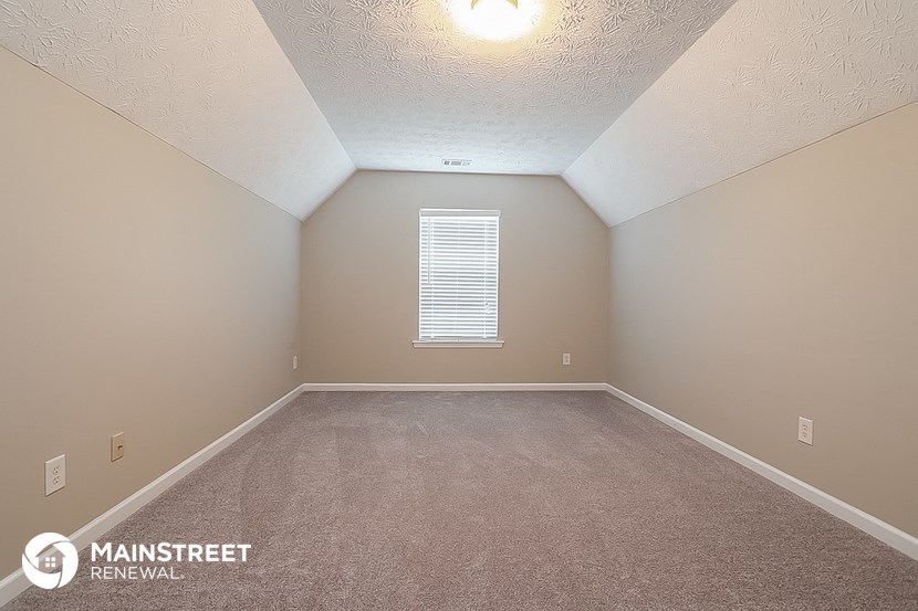 the upstairs bedroom has a carpeted floor and a window