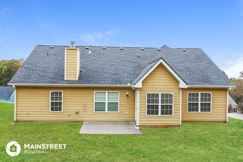 a yellow house with a grey roof on a lawn
