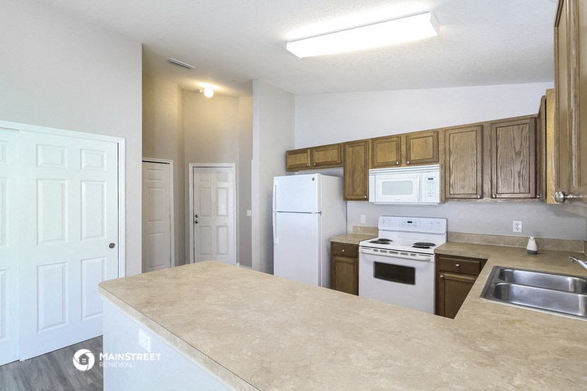 an empty kitchen with white appliances and wooden cabinets