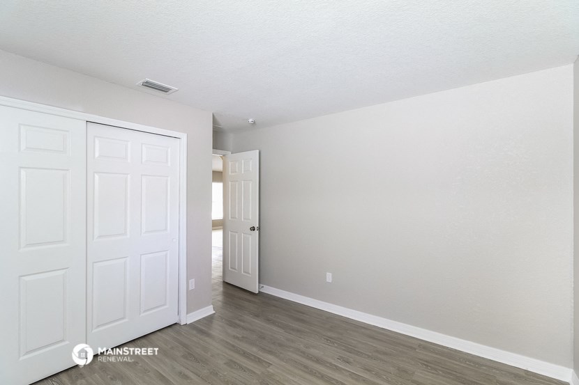 the living room of an apartment with white walls and wood floors
