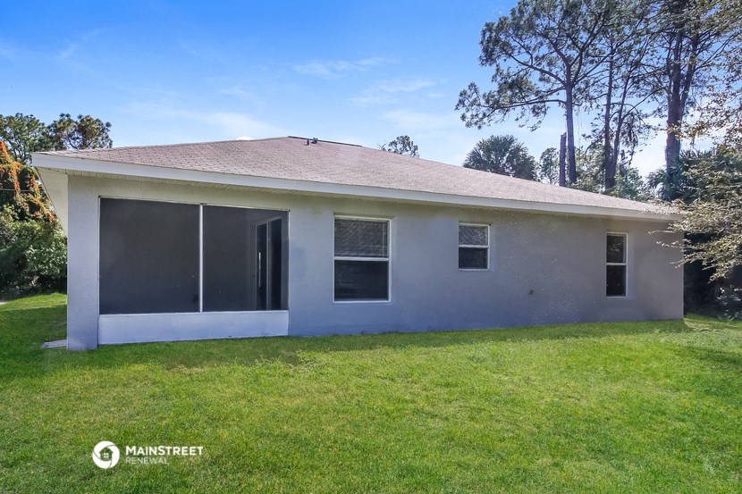 a small white house with a lawn and trees