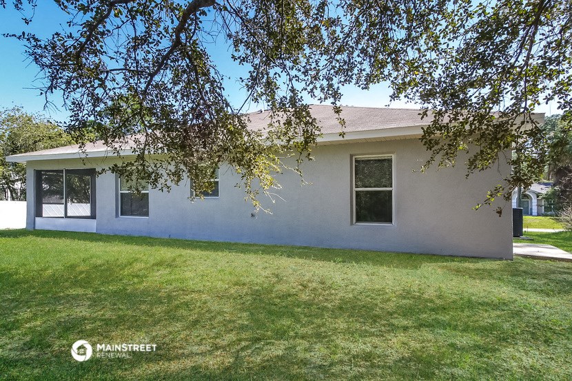 a white house with a lawn and a tree