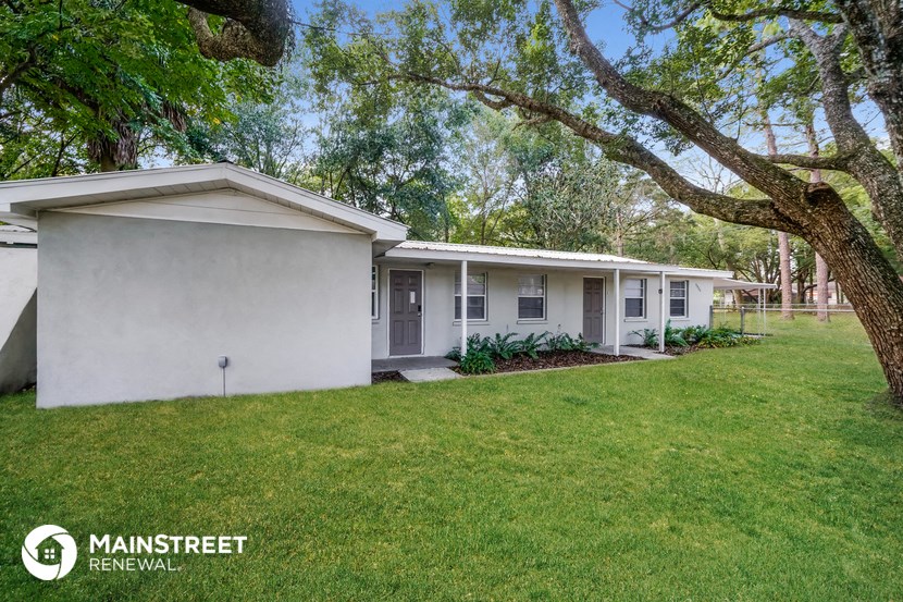 a small white house with a yard and trees