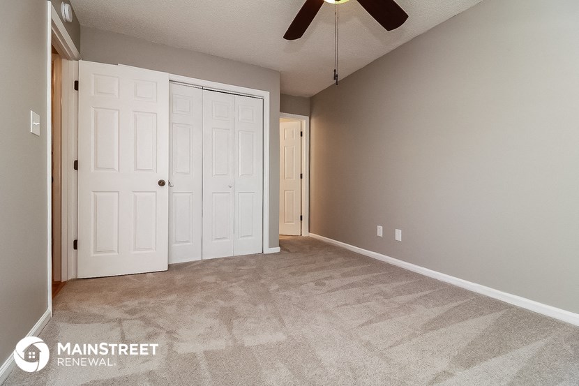 the spacious living room with carpeted floors and a ceiling fan