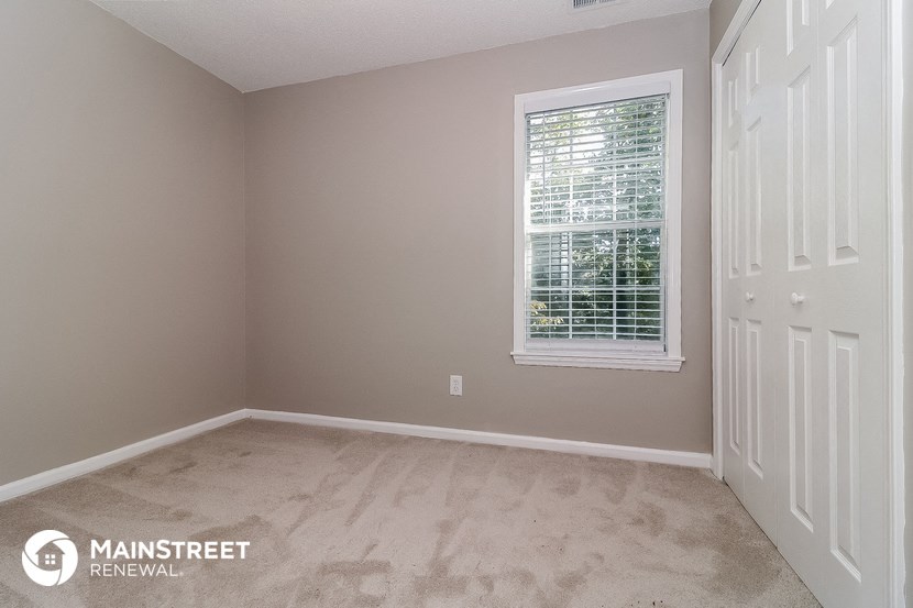 an empty bedroom with a window and a white door