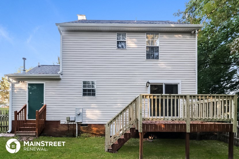 the back of a white house with a wooden deck