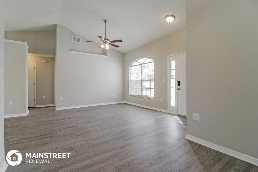 the living room of an empty house with a ceiling fan