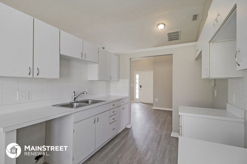 an empty kitchen with white cabinets and a sink