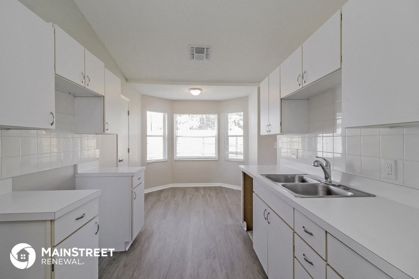 an empty kitchen with white cabinets and a sink