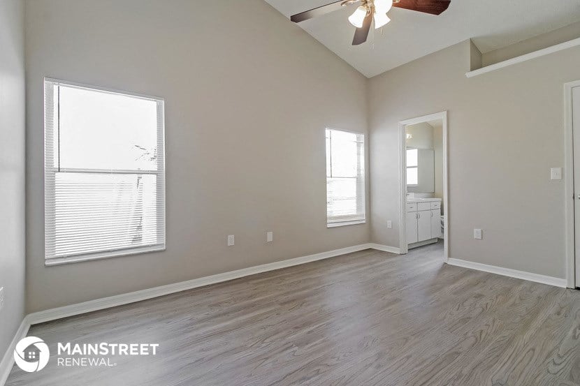 an empty living room with a ceiling fan and a window