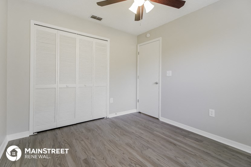 the living room of our studio apartment atrium with a ceiling fan and a closet