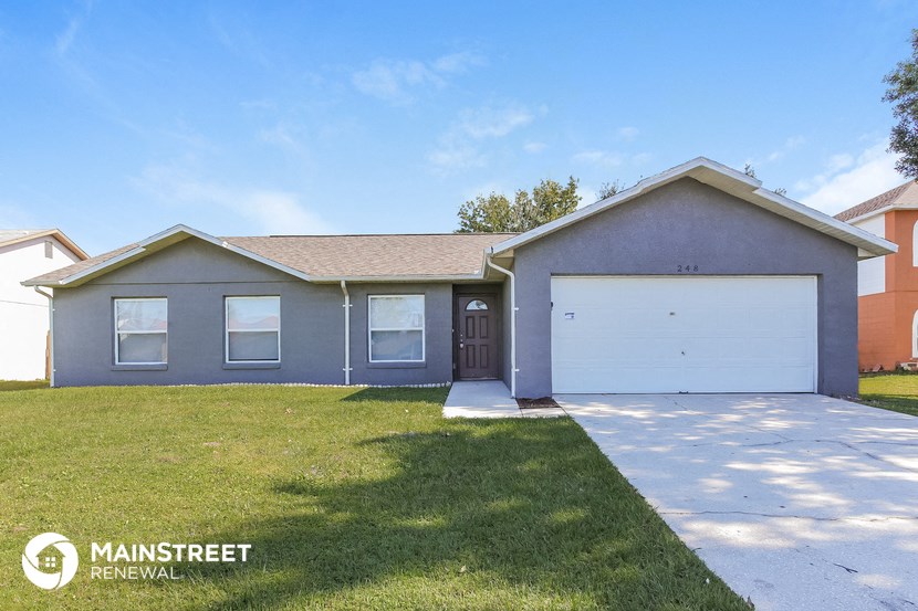 a blue house with a lawn and a white garage door