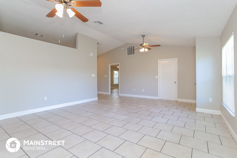 the spacious living room with ceiling fans and tile flooring