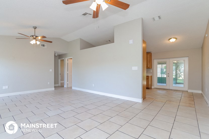 the spacious living room with tile flooring and ceiling fan